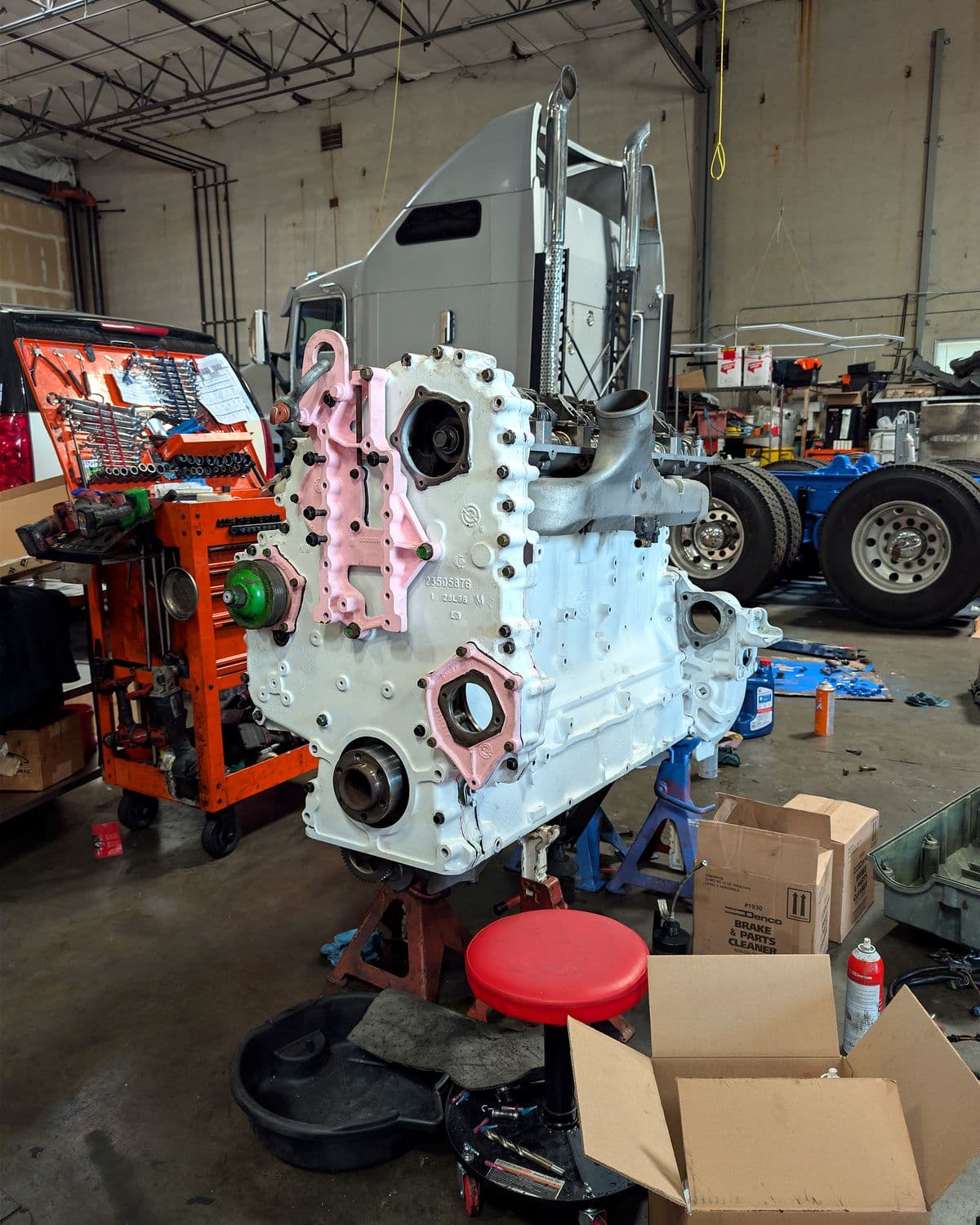 Diesel engine block on a stand in front of the custom truck it is being built for