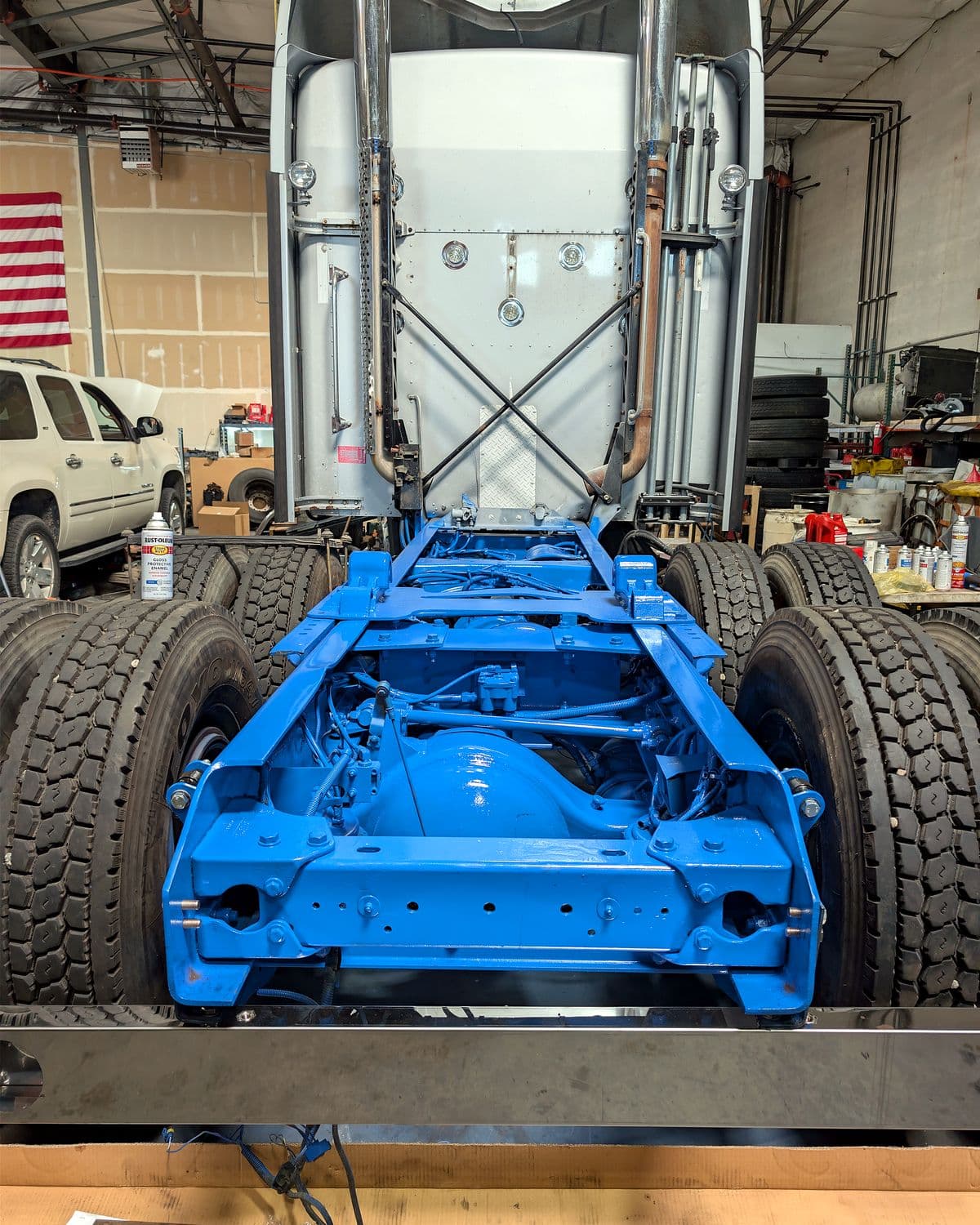 Rear frame and axles of a semi truck with freshly painted frame during a custom suspension build